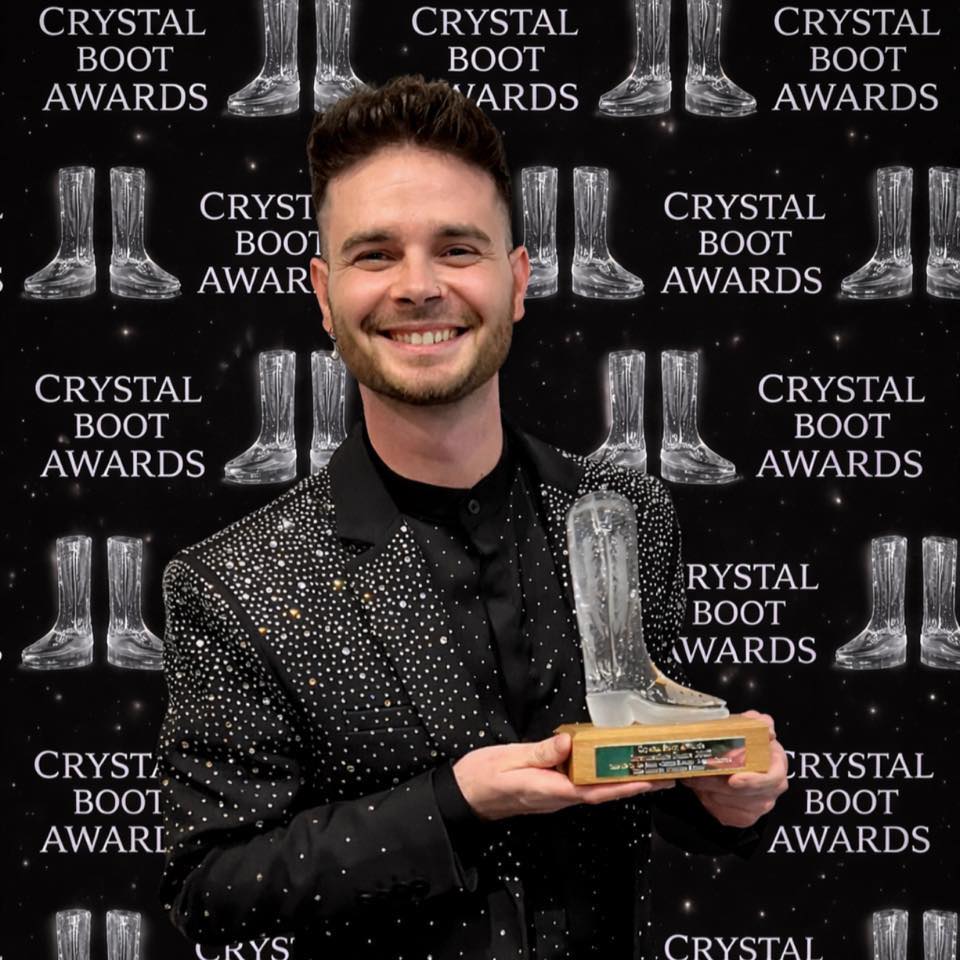 Picture of Gregory Danvoie posing with his own Crystal Boot Award.